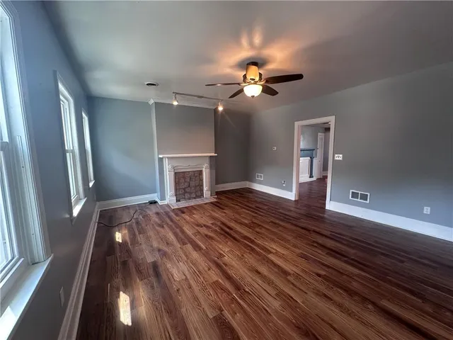 a view of a livingroom with a fireplace a chandelier fan and windows