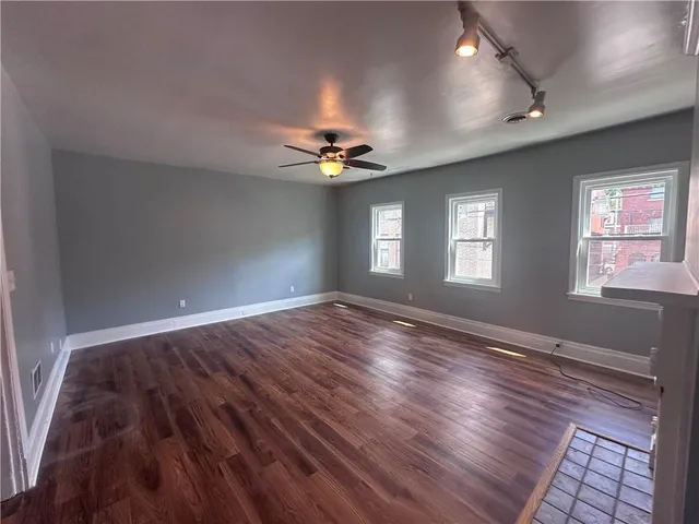 a view of an empty room with window and wooden floor