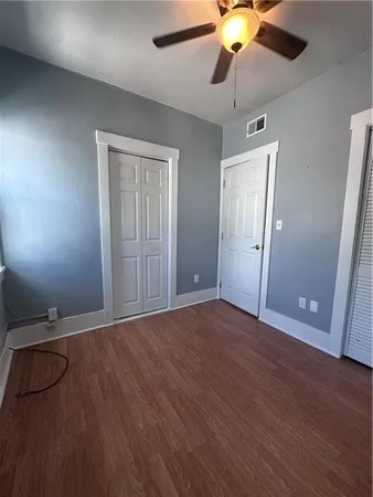 a view of an empty room with wooden floor and a ceiling fan