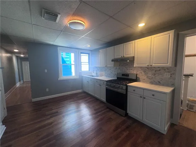 a kitchen with granite countertop a stove a sink and a refrigerator