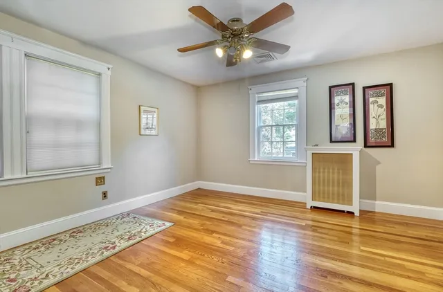a view of an empty room with window and wooden floor