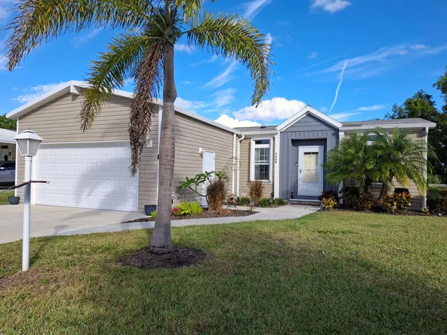 a front view of a house with a yard and palm trees