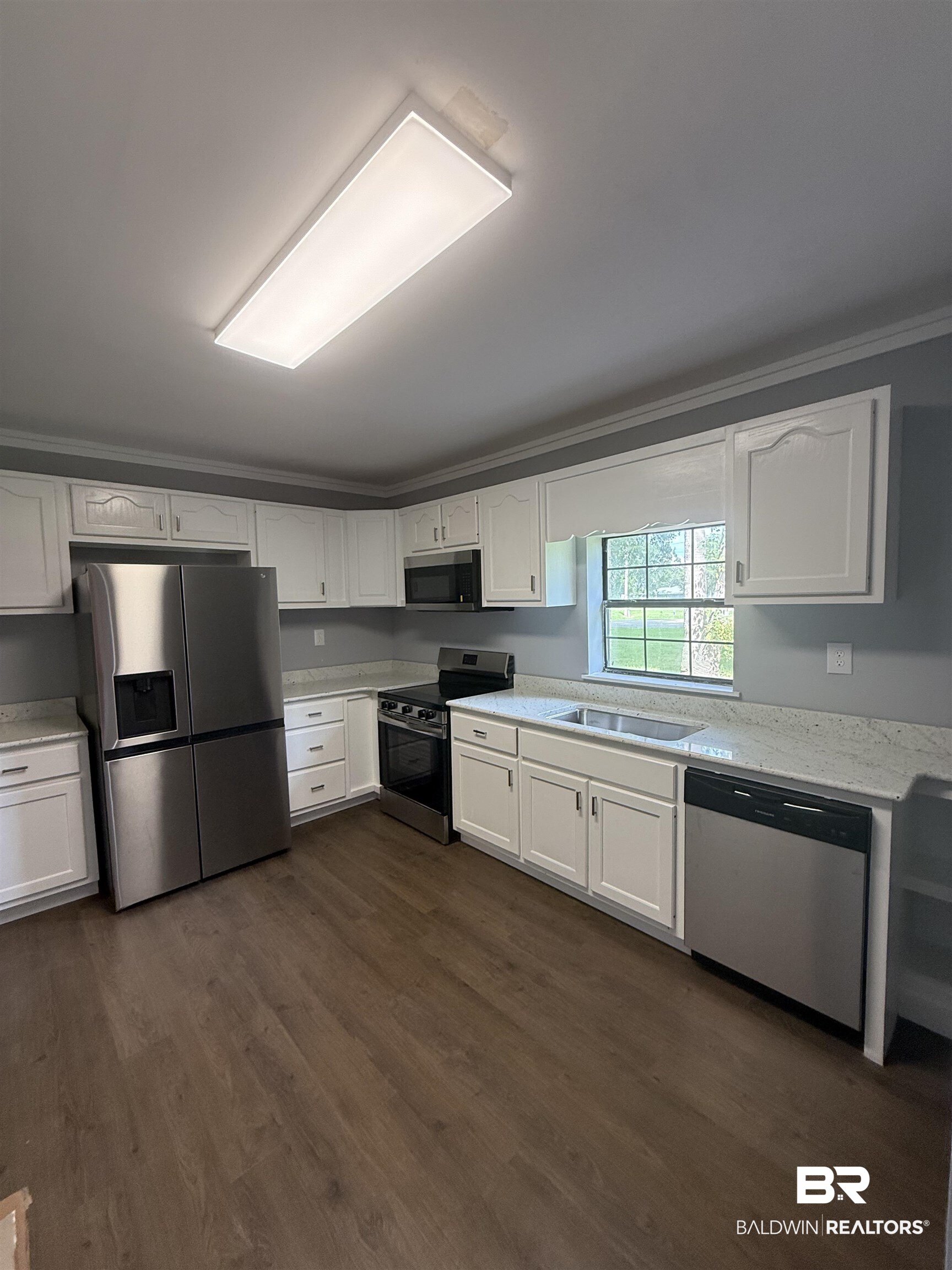 17440 Old Brady Road Bay Minette, AL 36507 - Photo 3 of 9 Kitchen with white cabinets, stainless steel appliances, dark wood finished floors, and light stone counters