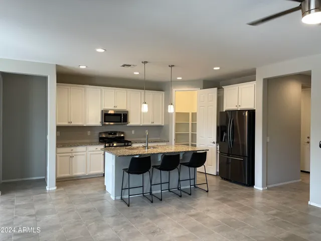 a kitchen with stainless steel appliances kitchen island granite countertop a refrigerator and a stove top oven