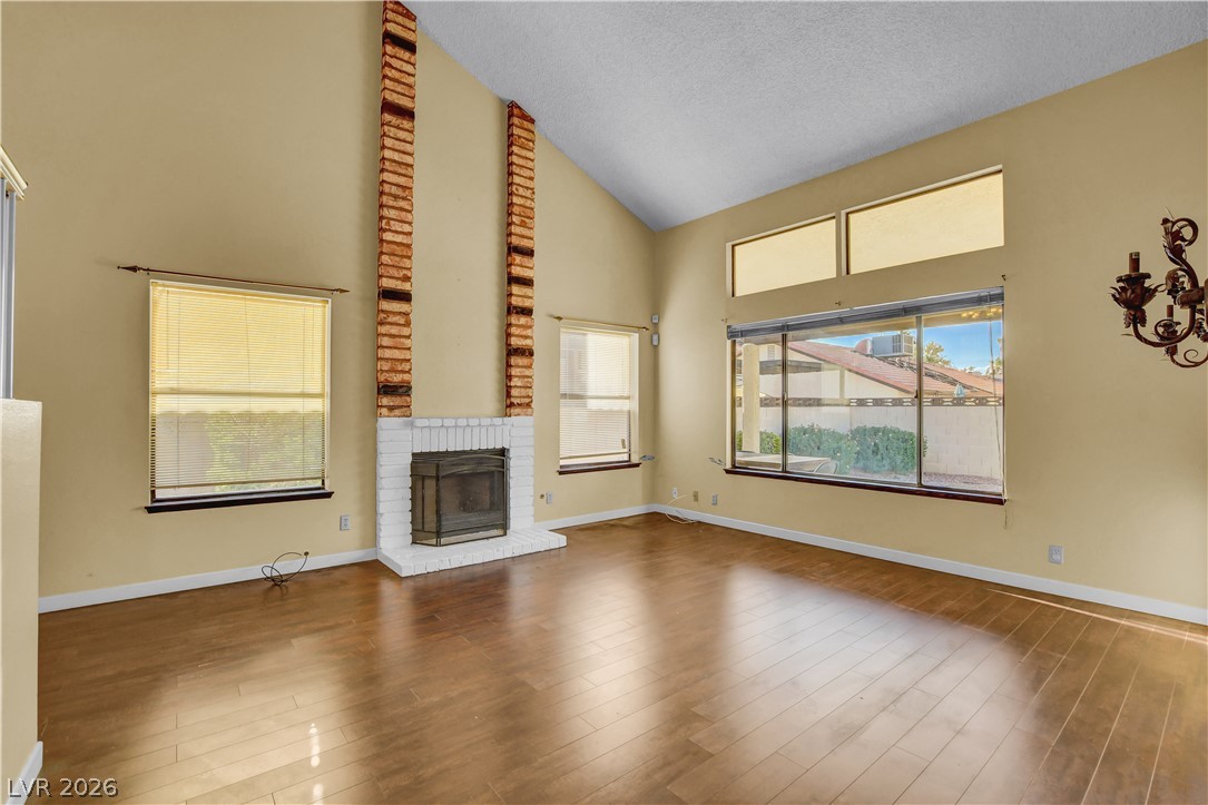 6440 Hartwood Road Las Vegas, NV 89108 - Photo 6 of 59 Vast vaulted ceilings complement rich hardwood floors, centered around a cozy fireplace with a brick surround.