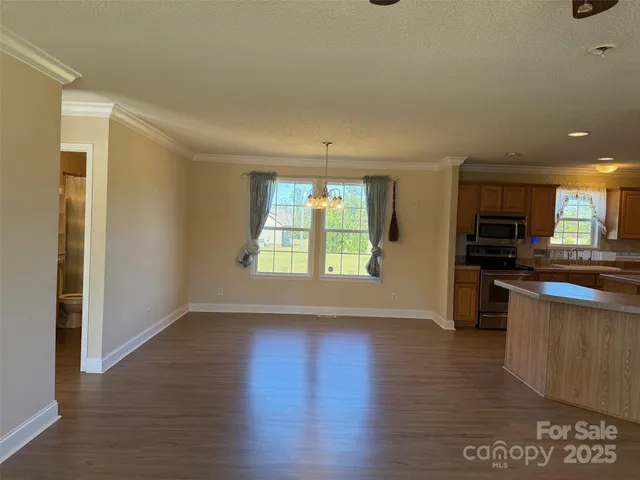 an empty room with wooden floor and a kitchen