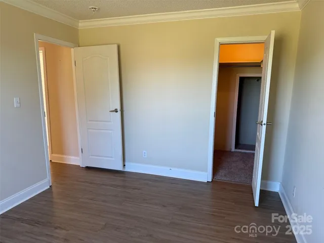 a view of an empty room with wooden floor and closet