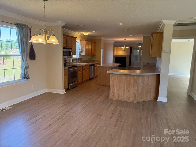 a kitchen with stainless steel appliances granite countertop a wooden floors a stove and a window