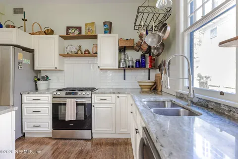 a kitchen with stainless steel appliances granite countertop a stove a refrigerator a dining table and chairs with wooden floor