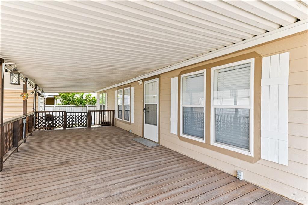 215 South Valley View Road, Unit 252 Donna, TX 78537 - Photo 3 of 19 Expansive covered porch featuring wood-finish flooring, a full-length metal awning, decorative railing, and multiple windows with white shutters