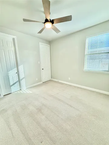 an empty room with windows and fan
