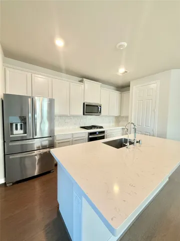 a kitchen with stainless steel appliances a refrigerator sink and white cabinets