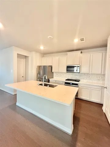 a large kitchen with kitchen island a sink a stove and white cabinets