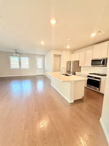 a large kitchen with kitchen island a stove a sink a refrigerator and cabinets