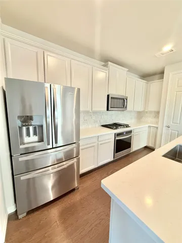 a kitchen with granite countertop white cabinets and stainless steel appliances