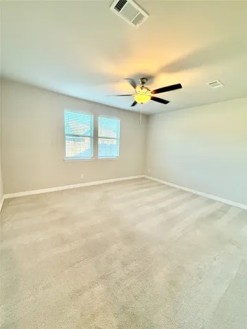 an empty room with a ceiling fan and window