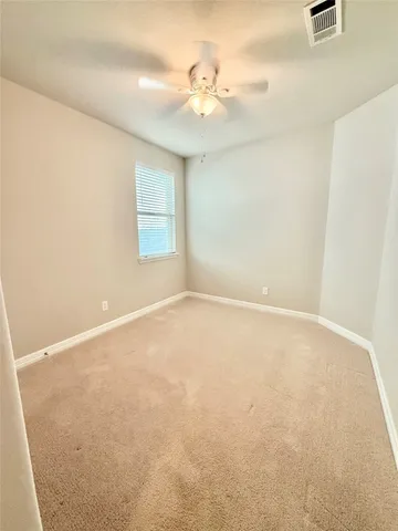 an empty room with a chandelier fan and windows