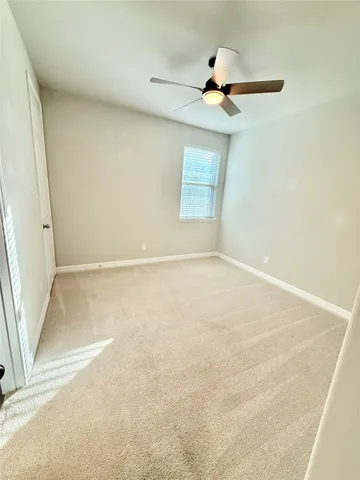 an empty room with a ceiling fan and window