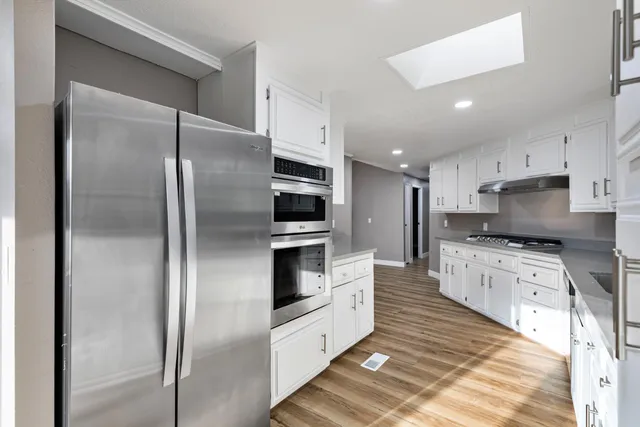 a large kitchen with cabinets stainless steel appliances and a counter top space