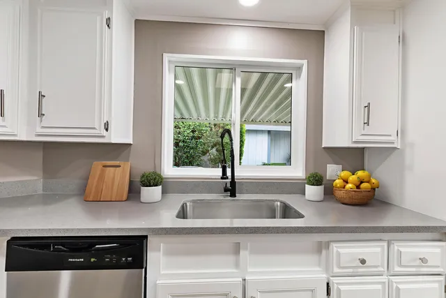 a kitchen with a stove and white cabinets with wooden floor