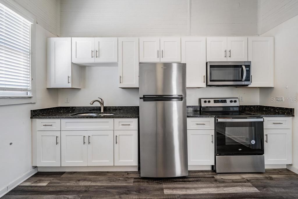 2319 West Aileen Street, Unit B Tampa, FL 33607 - Photo 9 of 19 a kitchen with stainless steel appliances granite countertop a refrigerator stove a sink and white cabinets