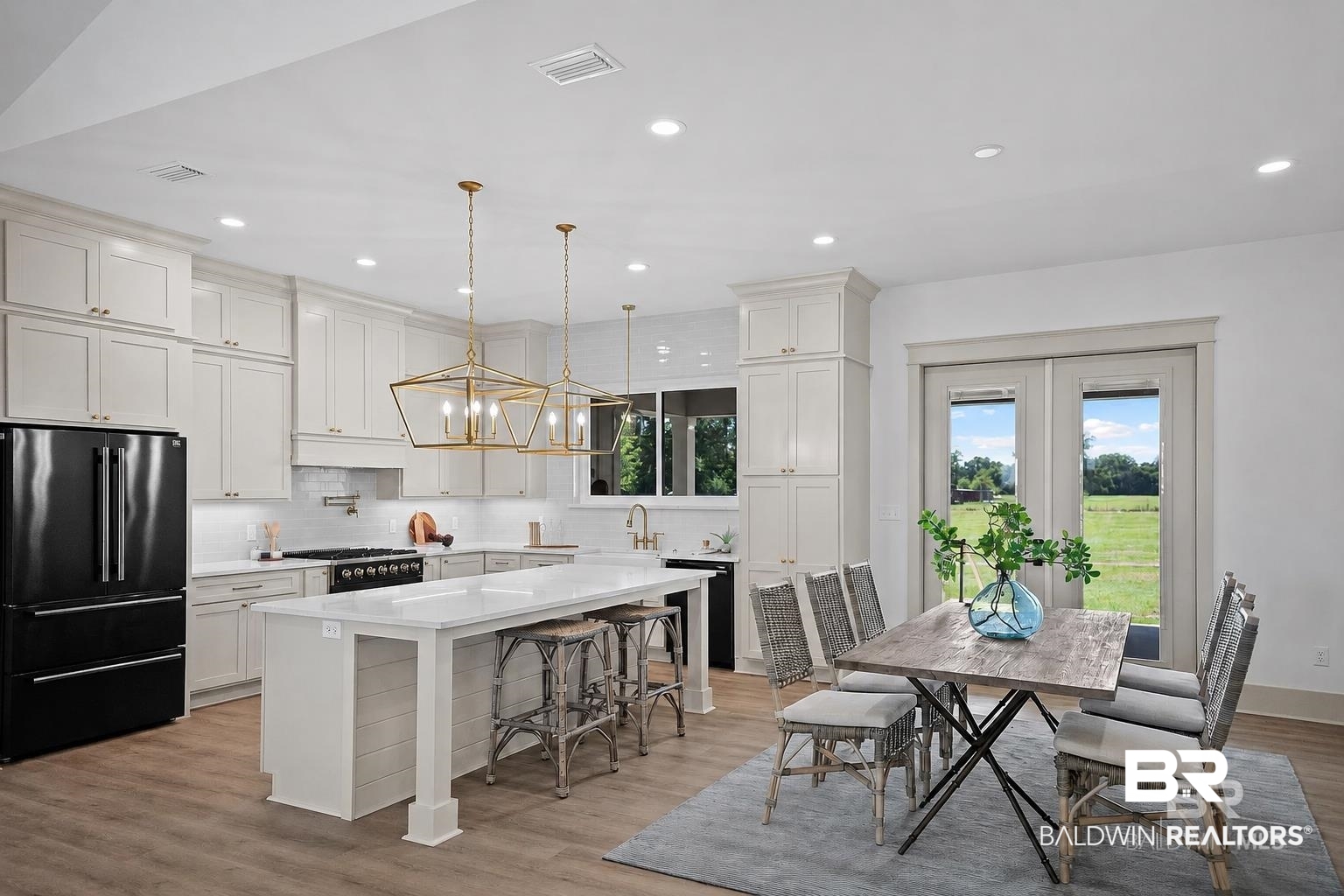 13111 Gopher Court Elberta, AL 36530 - Photo 7 of 41 Open-concept kitchen and dining area featuring a large center island with seating, white shaker cabinetry, and a black stainless steel appliance package