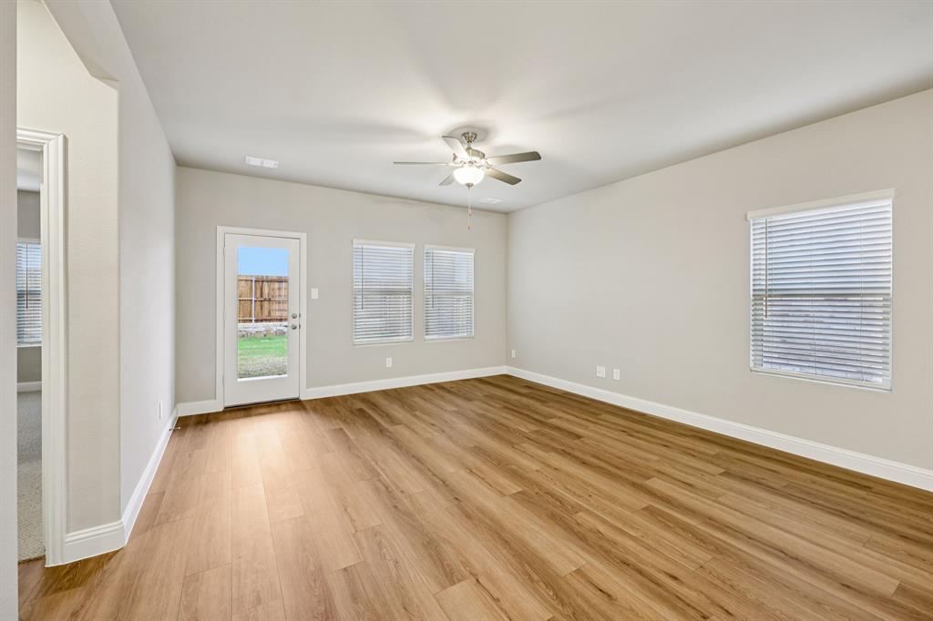 1721 Arches Road Anna, TX 75409 - Photo 9 of 39 an empty room with wooden floor ceiling fan and windows