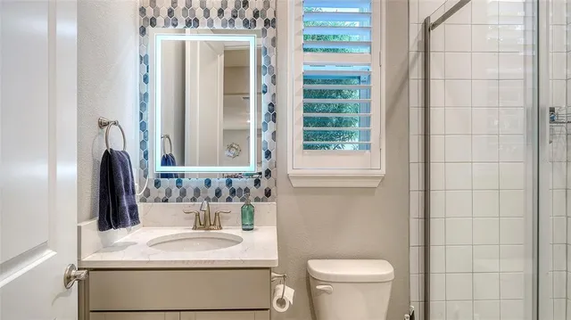 a bathroom with a granite countertop sink toilet and mirror