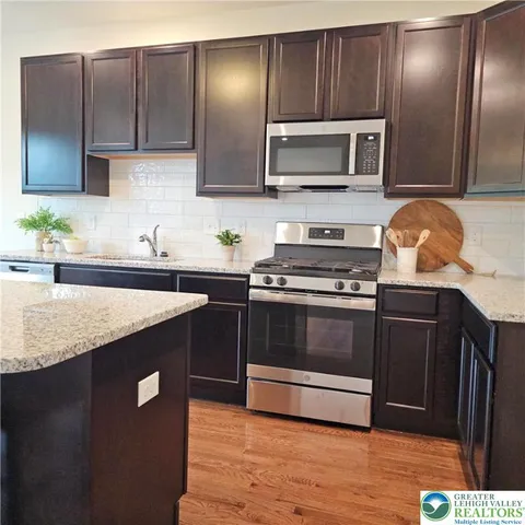 a kitchen with stainless steel appliances granite countertop wooden cabinets a stove top oven a sink and dishwasher