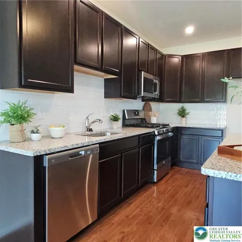 a kitchen with stainless steel appliances granite countertop wooden cabinets a sink and dishwasher