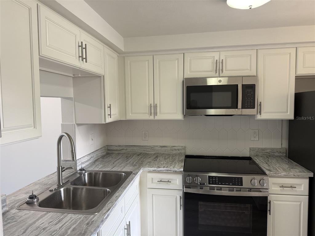 4413 Sunstate Drive New Port Richey, FL 34652 - Photo 3 of 14 a kitchen with stainless steel appliances granite countertop a sink stove and microwave
