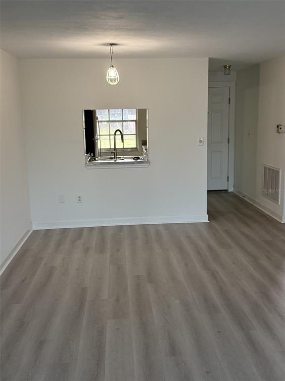 4413 Sunstate Drive New Port Richey, FL 34652 - Photo 5 of 14 an empty room with wooden floor and mirror