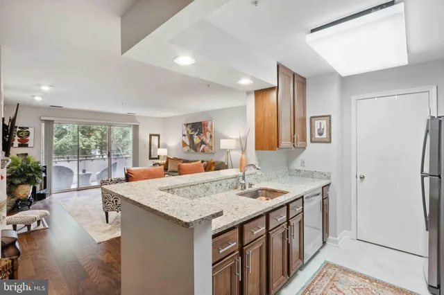 a view of kitchen island with stainless steel appliances granite countertop sink refrigerator dining table and chairs