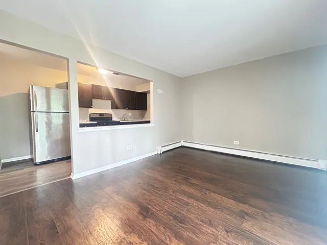 a view of a kitchen with a fridge and wooden floor