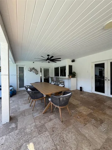a backyard of a house with wooden table and chairs