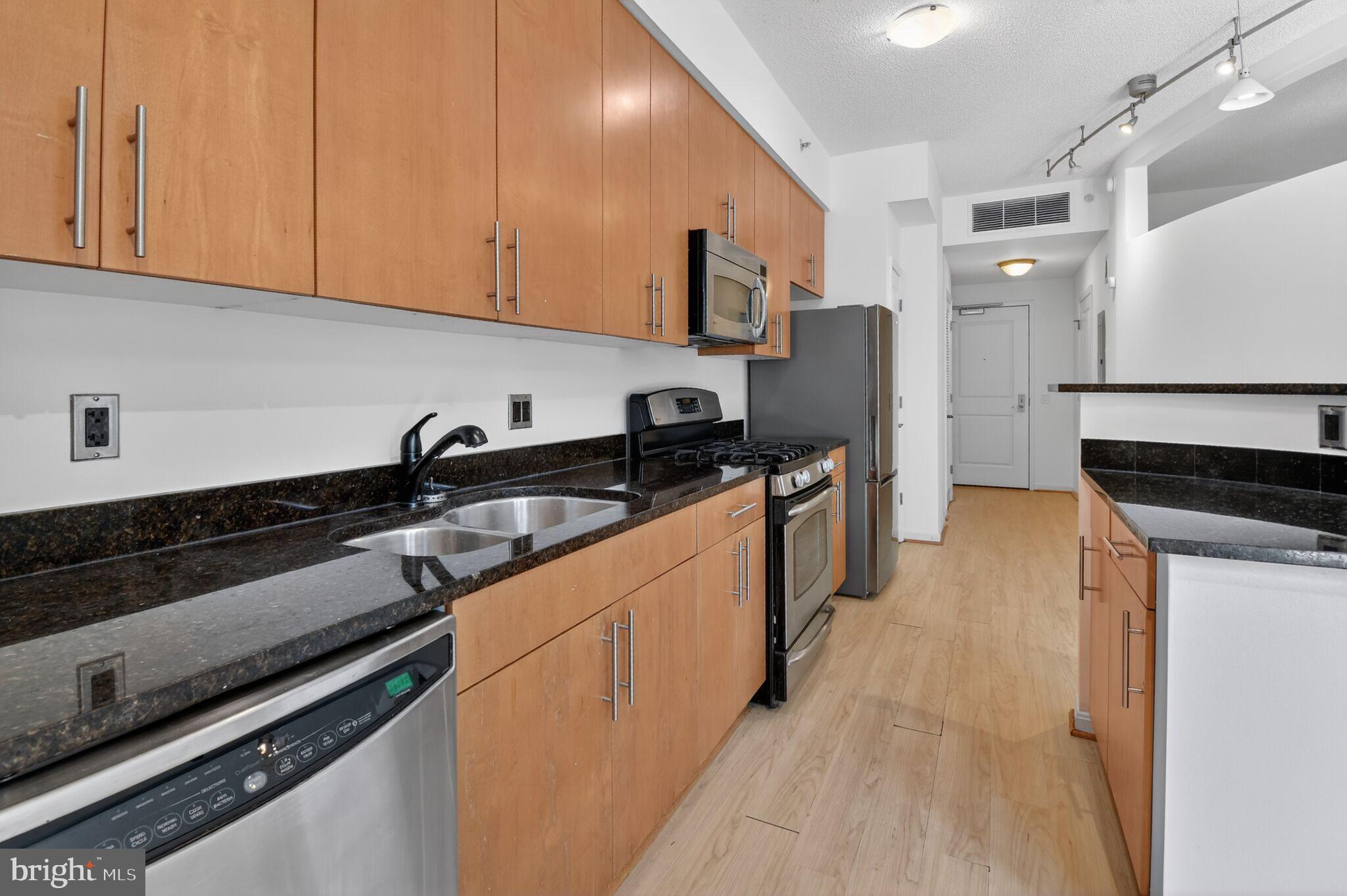 1390 Kenyon Street Northwest, Unit 319 Washington, DC 20010 - Photo 10 of 38 a kitchen with stainless steel appliances a sink dishwasher stove refrigerator and cabinets