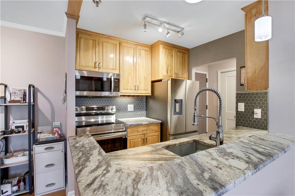 a kitchen with stainless steel appliances kitchen island granite countertop a refrigerator oven a sink dishwasher and white cabinets with wooden floor