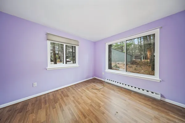 a view of an empty room with a window and wooden floor