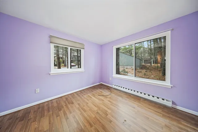 a view of an empty room with a window and wooden floor