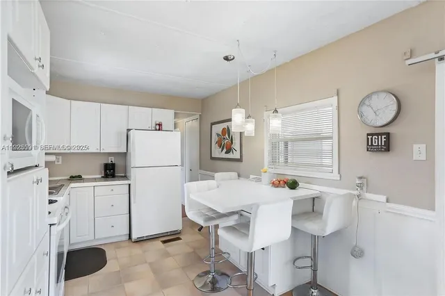 a dining room with stainless steel appliances furniture a large window and a refrigerator