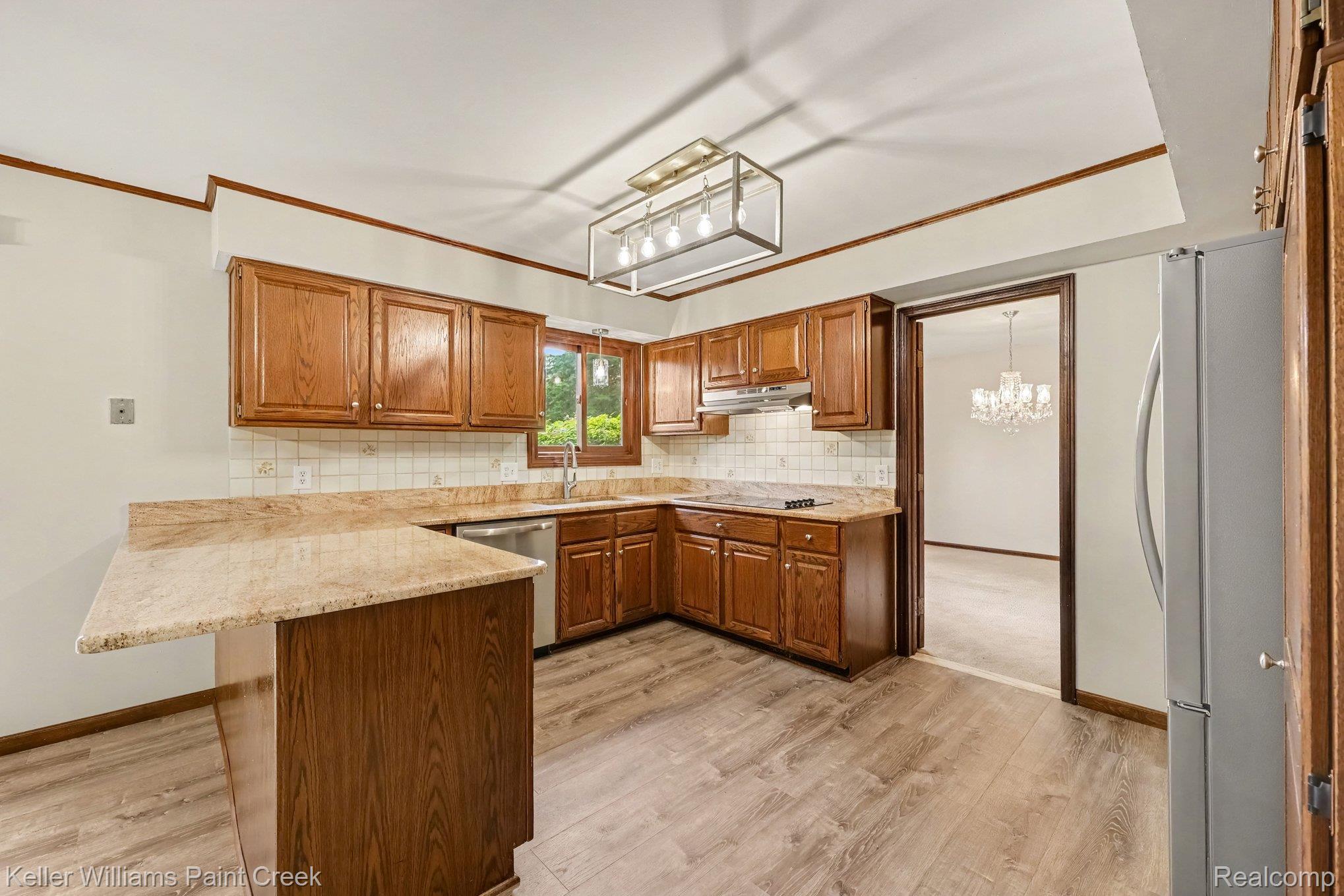 2717 Powderhorn Ridge Road Rochester, MI 48309 - Photo 4 of 48 Wood-finish flooring, ample wood cabinetry, light-toned countertops, and a modern rectangular ceiling fixture