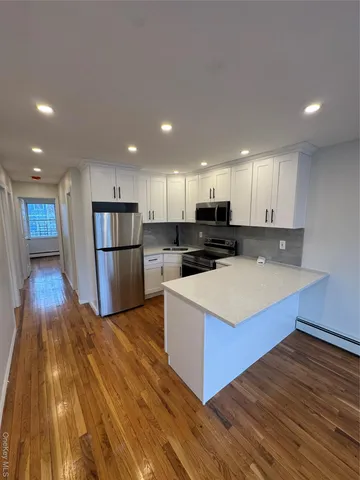 a view of a kitchen with kitchen island a sink wooden floor and a large window