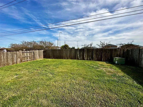 a view of a backyard with grass & fence
