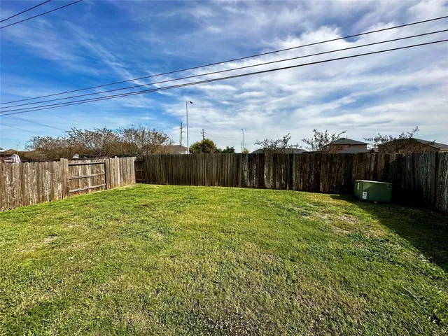 a view of a backyard with grass & fence