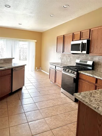 a kitchen with stainless steel appliances granite countertop a stove a sink and a microwave