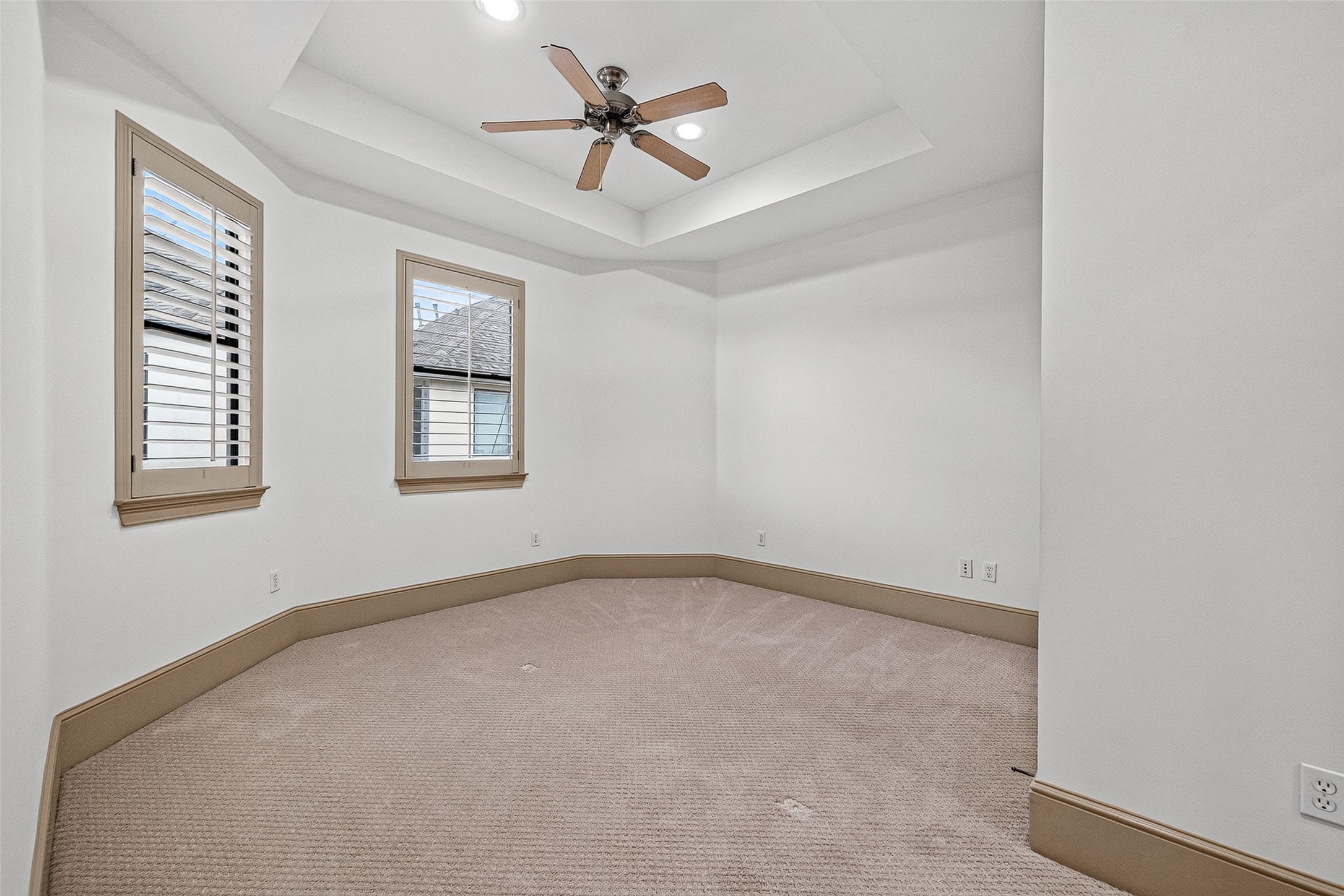 2034 Colquitt Street, Unit A Houston, TX 77098 - Photo 33 of 41 This 3rd floor ensuite bedroom features a cozy, carpeted space with a tray ceiling and recessed lighting. It includes two windows with wooden shutters and a ceiling fan, offering a comfortable and inviting atmosphere.