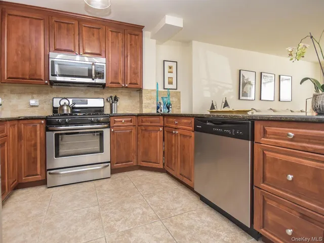 a kitchen with stainless steel appliances granite countertop a stove top oven a sink dishwasher and cabinets with wooden floor