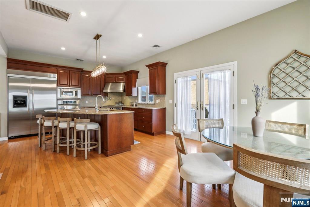 28 George Street Saddle Brook, NJ 07663 - Photo 12 of 50 a kitchen with stainless steel appliances a dining table chairs and wooden floor