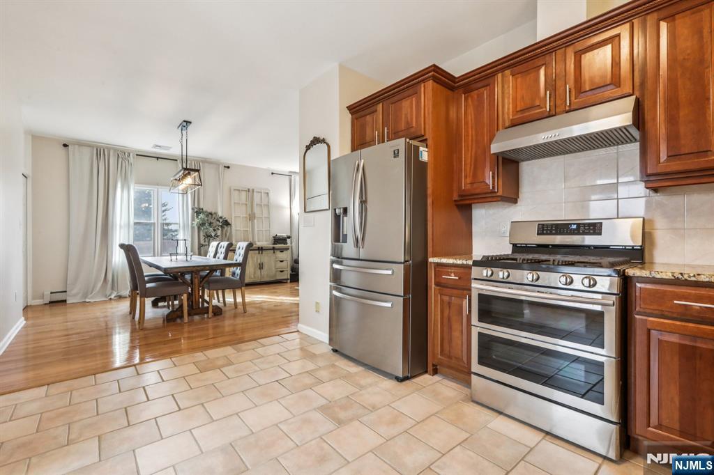 28 George Street Saddle Brook, NJ 07663 - Photo 23 of 50 a kitchen with granite countertop a refrigerator stove top oven dining table and a window