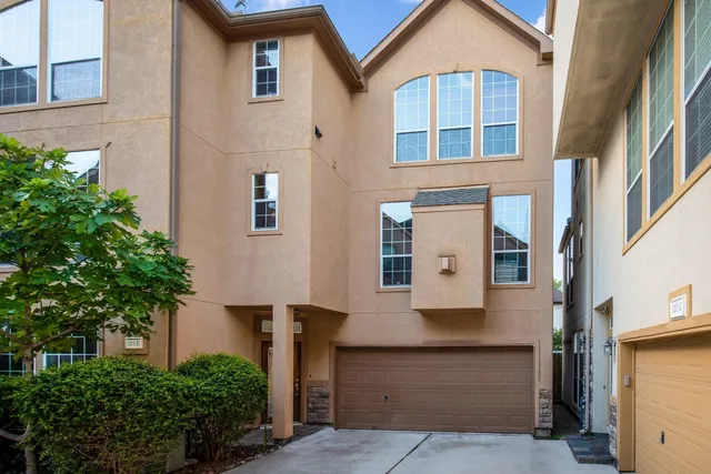 front view of a brick house with a yard and potted plants